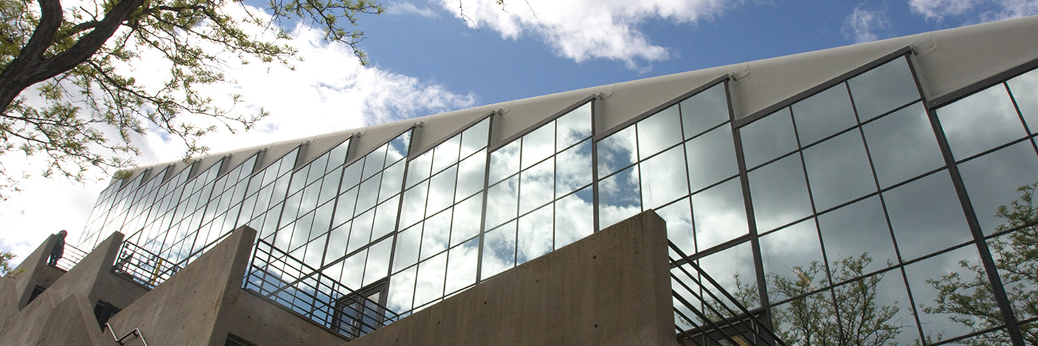 Image of exterior of Gund Hall tray windows with the sky reflecting