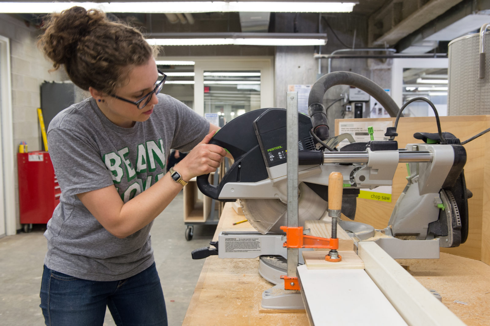 Student using compound mitre saw within the woodshop of the Fabrication Lab.