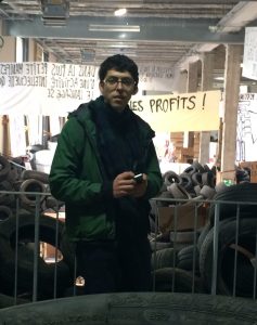 picture of Aleksandr Bierig standing in front of a pile of tires and a fence