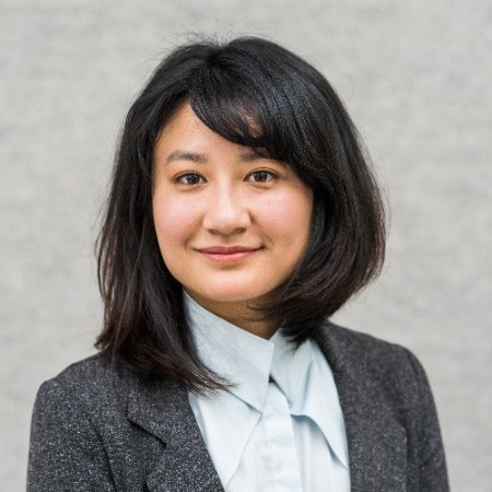 Weijia Song wears a white blouse and grey suit jacket, and is looking at the camera.