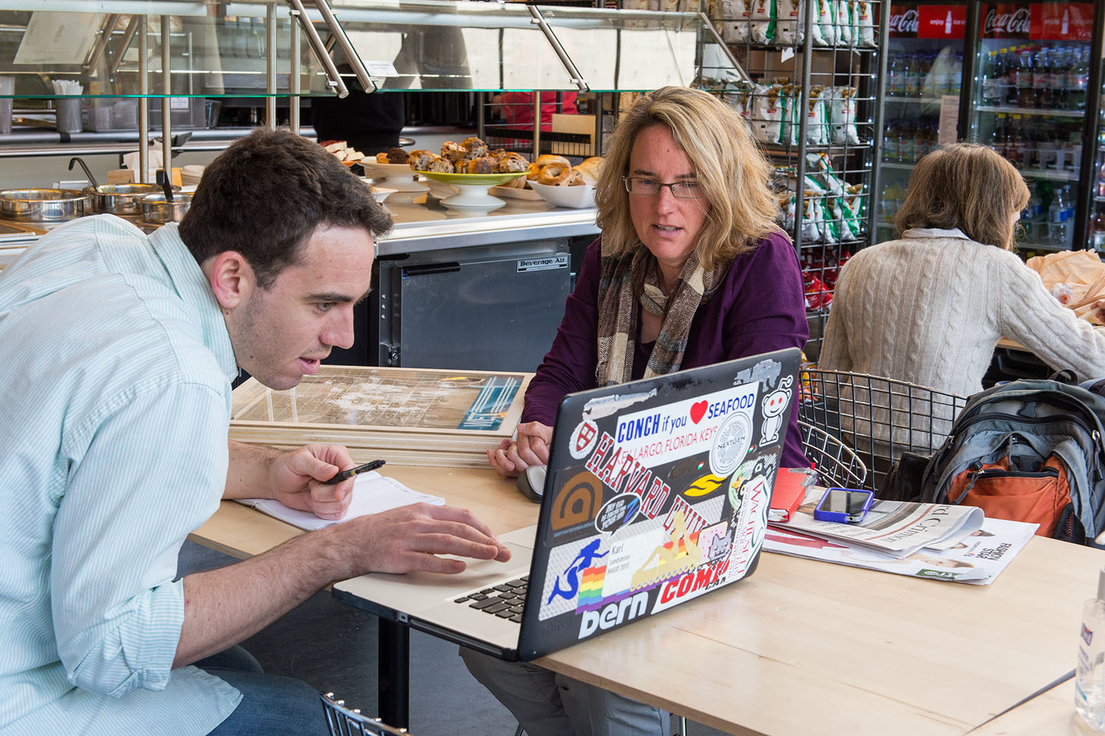 two people seated at a table looking at a shared laptop computer