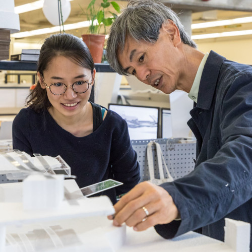 A student and faculty member examine a student project together.