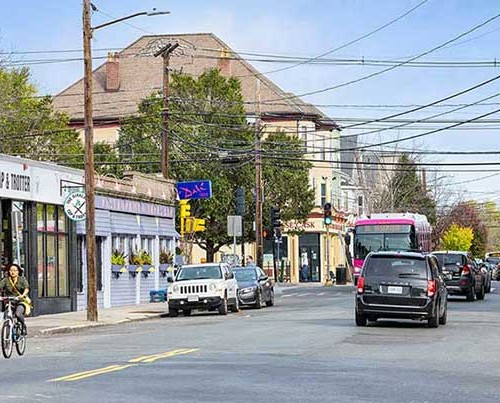 A busy street with cars, buses, and a cyclist.