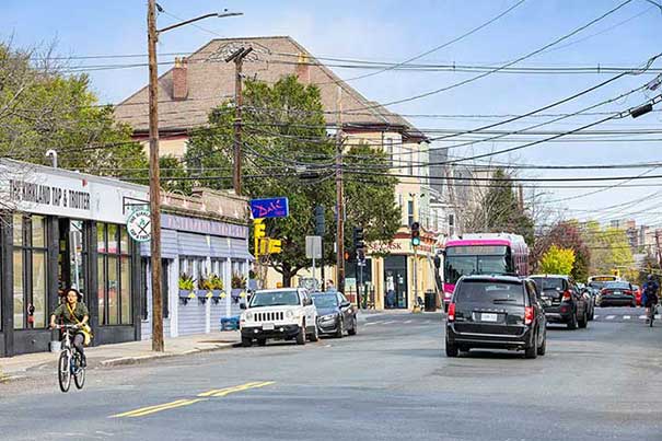 A busy street with cars, buses, and a cyclist.