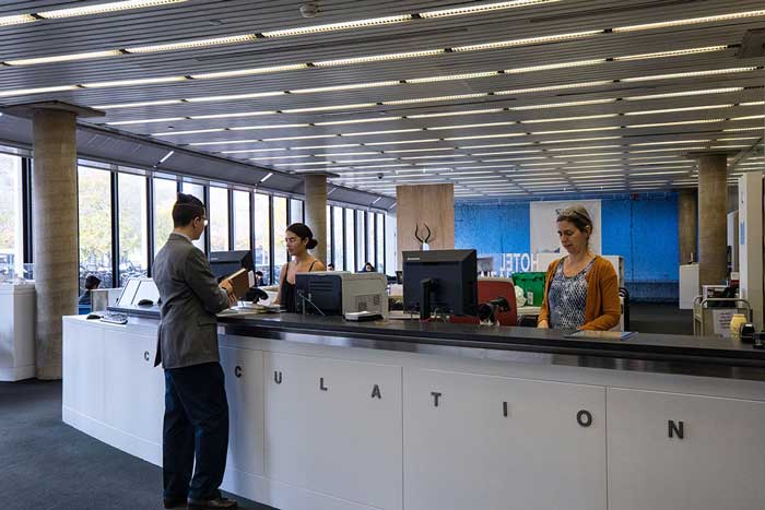 A person checks out a book at the library circulation desk.