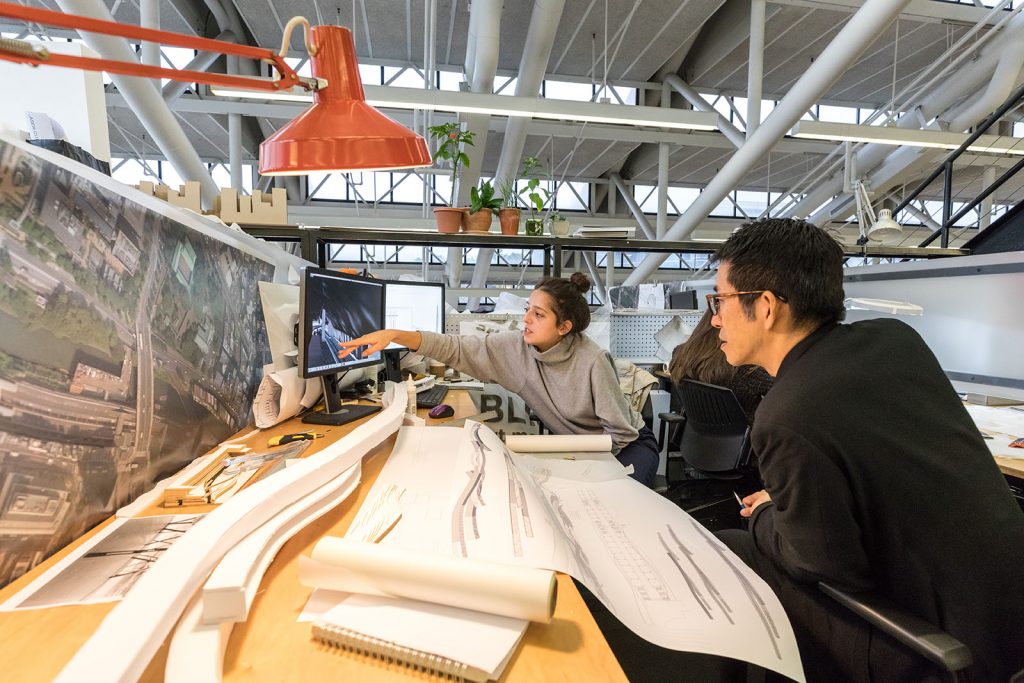 A student points at a document at a desk as another person watches.