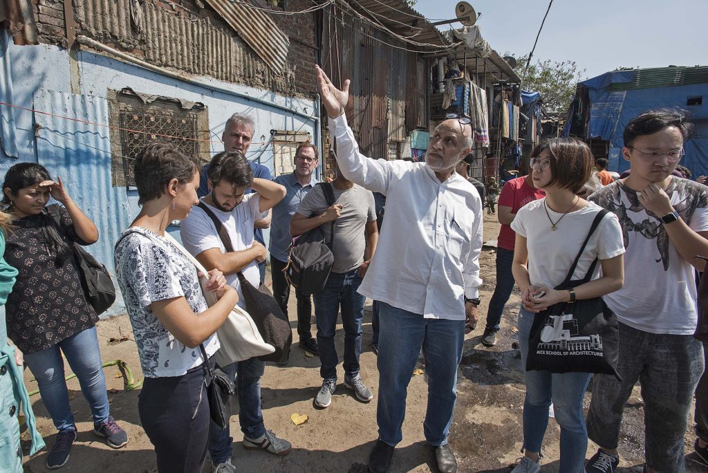 Three hundred families live adjacent to existing warehouses. They do not have housing provision rights because of living over the sidewalk. Professor Rahul Mehrotra (center) talks to the group.