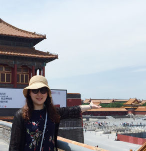 picture of Jingping Liu standing on a ledge looking out over a busy square