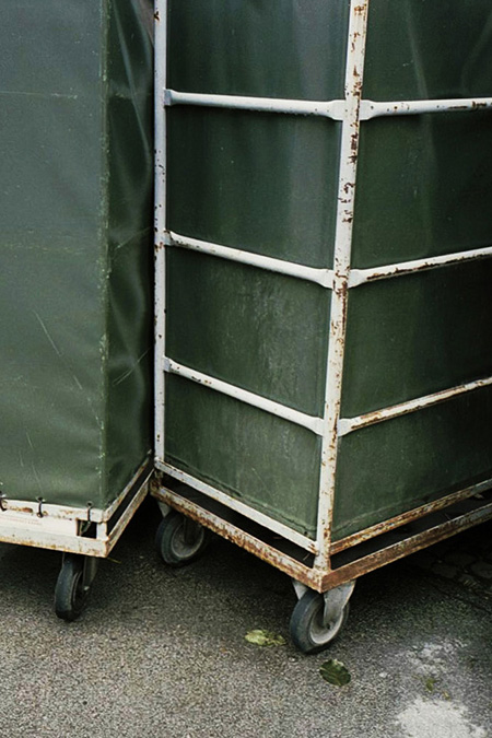 Abstract image of canvas and metal carts on pavement.