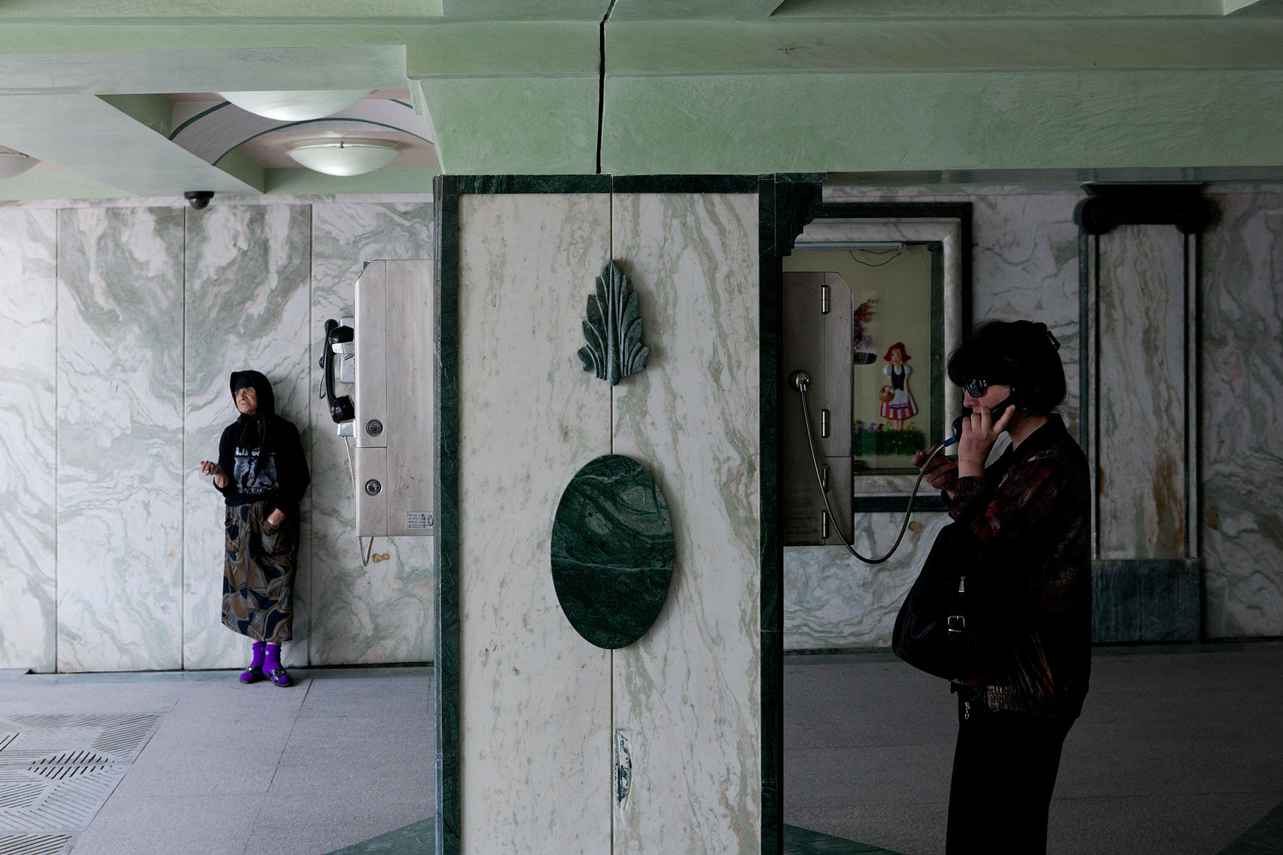 Photo of lobby including woman speaking on public phone