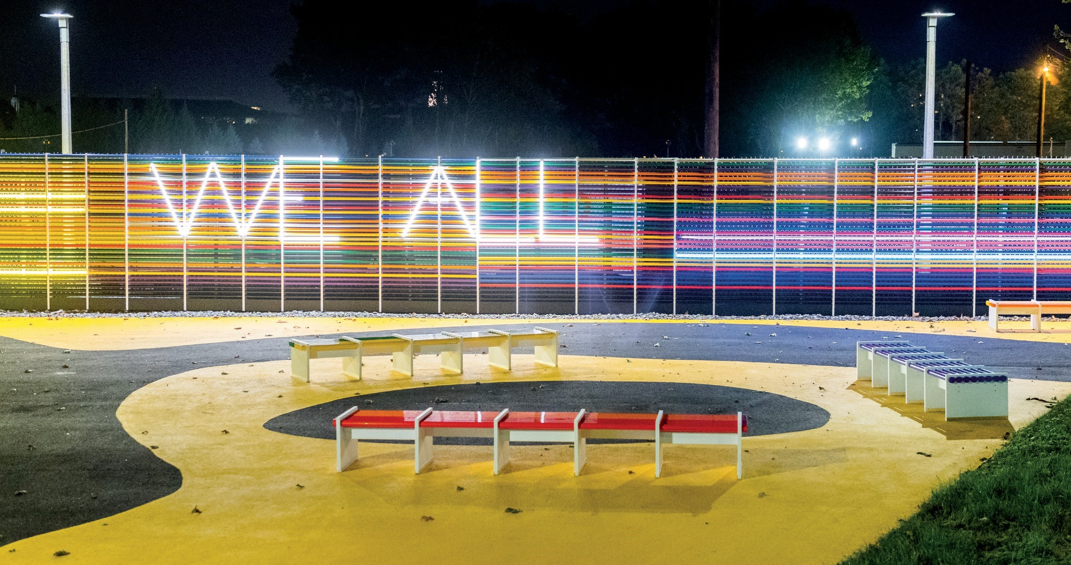 Colorful neon letters spelling out We All on a fence.