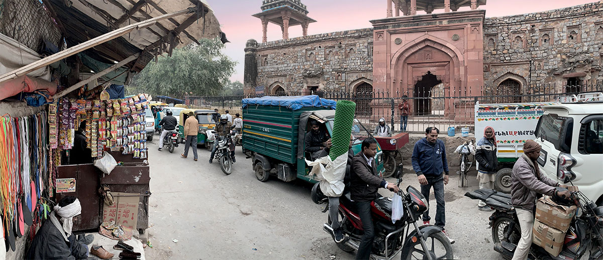 Bustling streetscape of Mehrauli urban village with a protected monument in the background