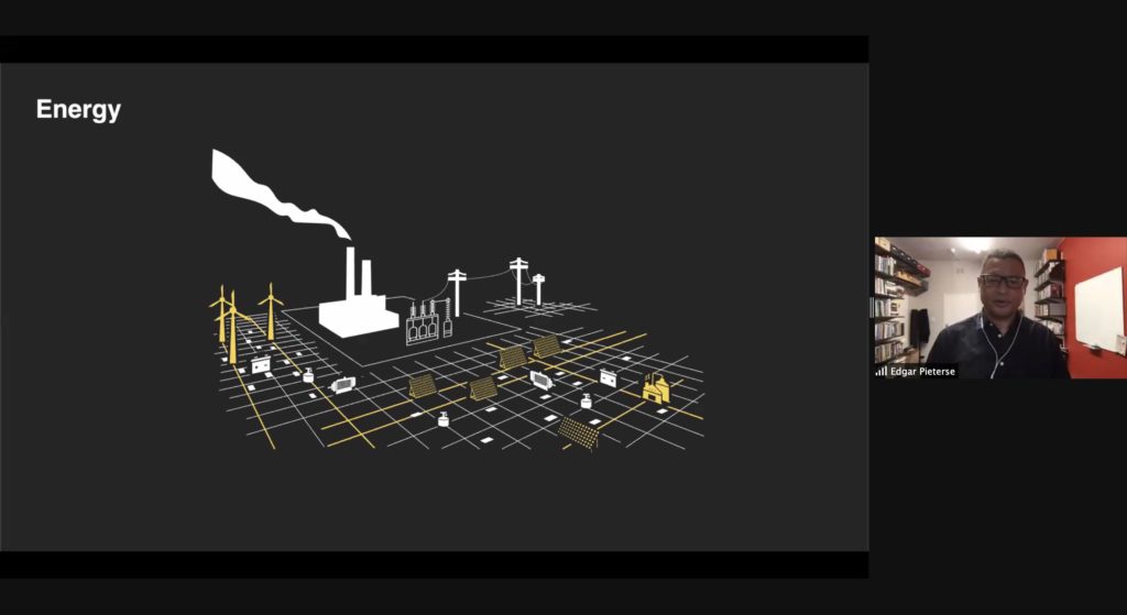 Screenshot of a presentation by Edgar Pieterse on Zoom. Pieterse is visible is on the right side of the screen. The presentation shows an illustration of an urban area with the title "Energy."