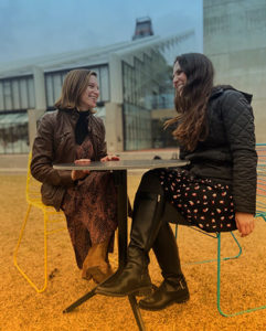  Taylor Greenberg Goldy and Sarah Kovar sit at a table laughing in the Gund courtyard