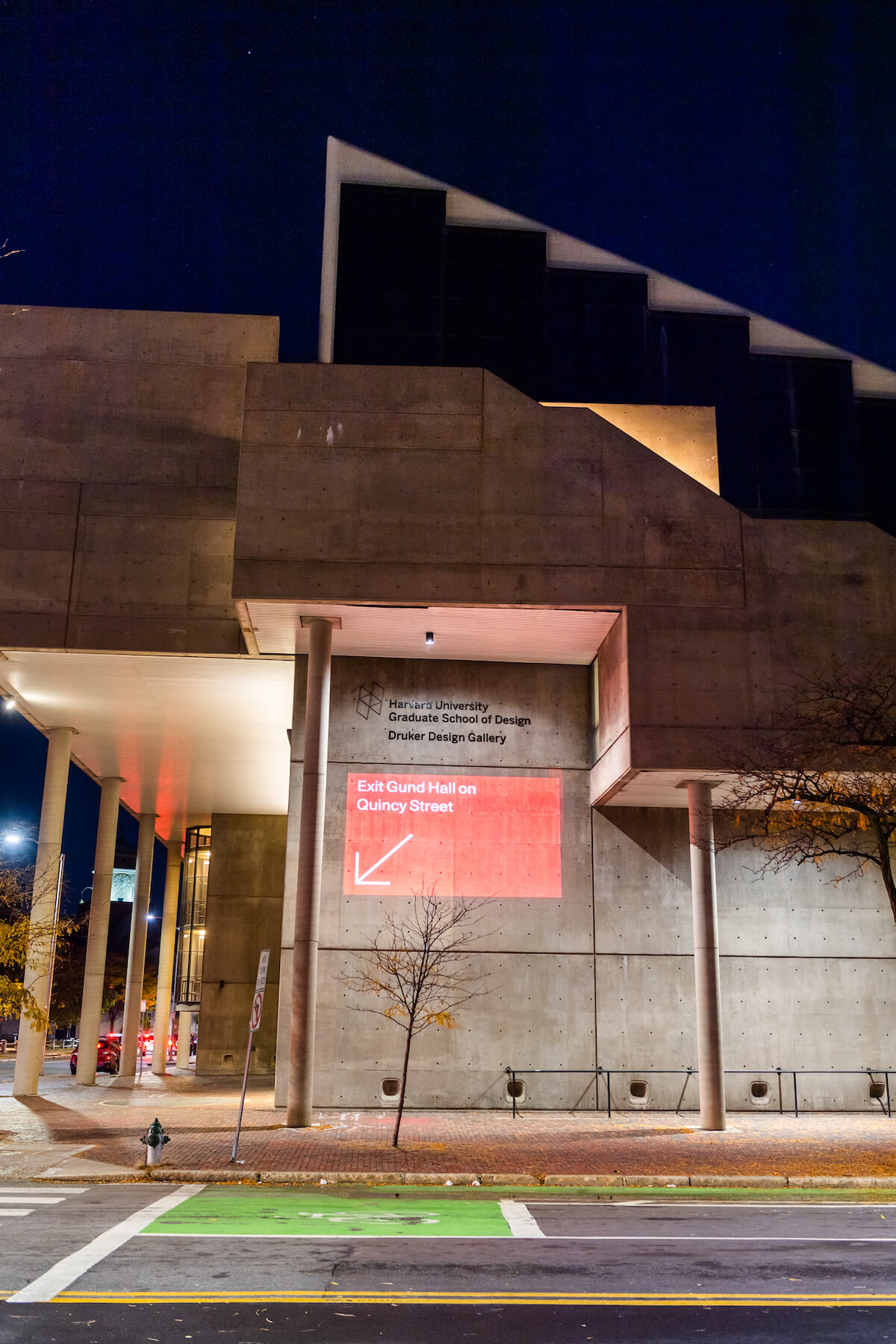 Gund Hall at night with projection illuminated on the side of the building.