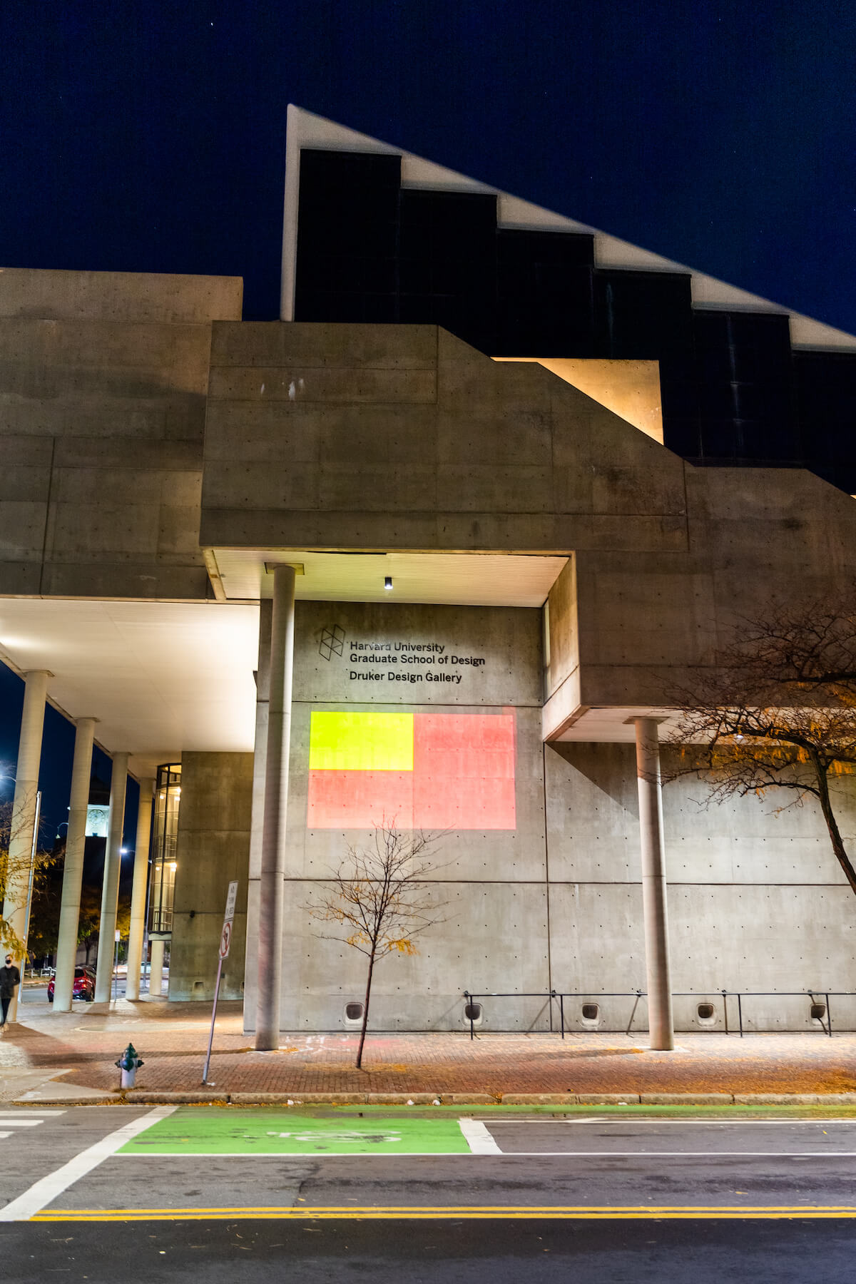 Gund Hall at night with projection illuminated on the side of the building.