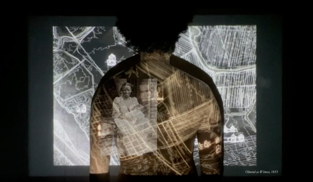 Still of video showing visual projections showing historic plantation life onto man's back