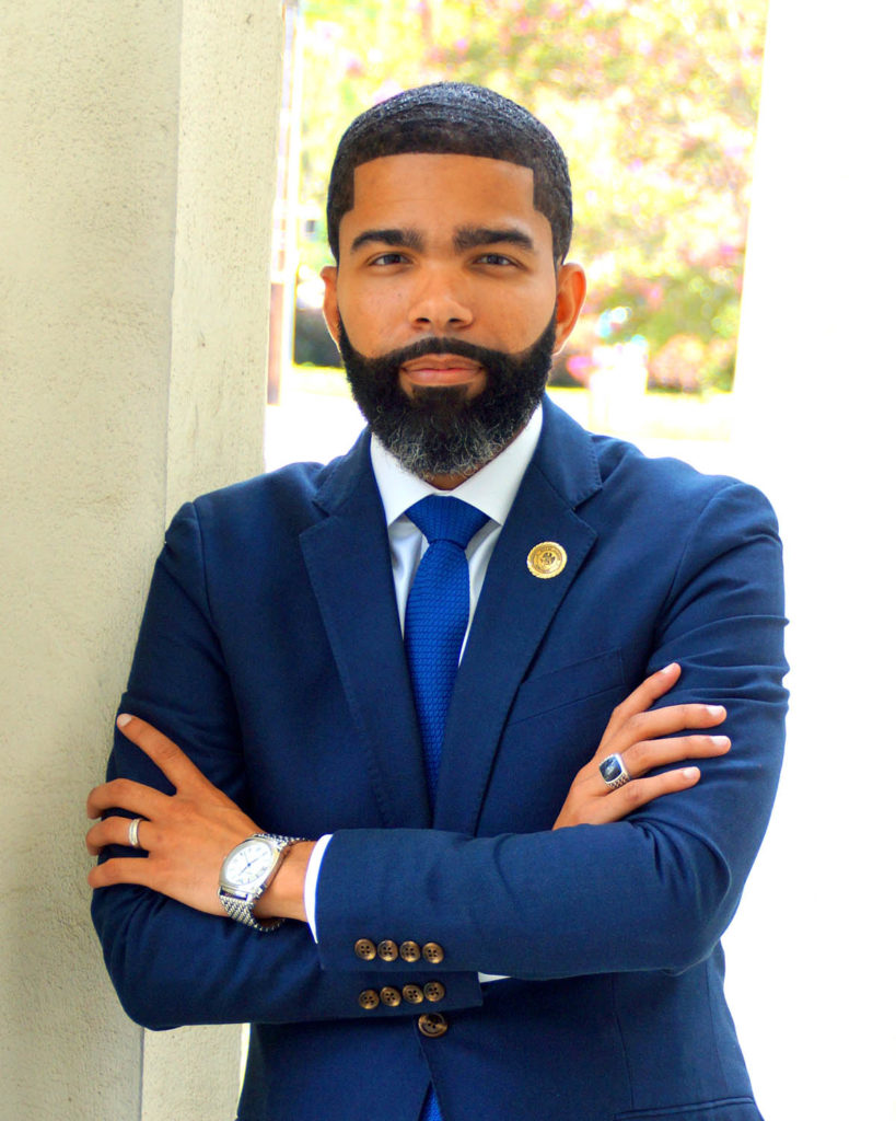 Headshot of Mayor Lumumba, who wears a blue suit and tie and stands with his arms crossed.