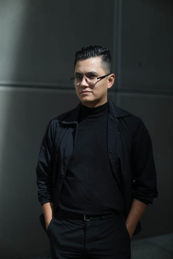 Headshot of José Esparza Chong Cuy, who wears glasses and all-black, and stands with his hands in his pockets.