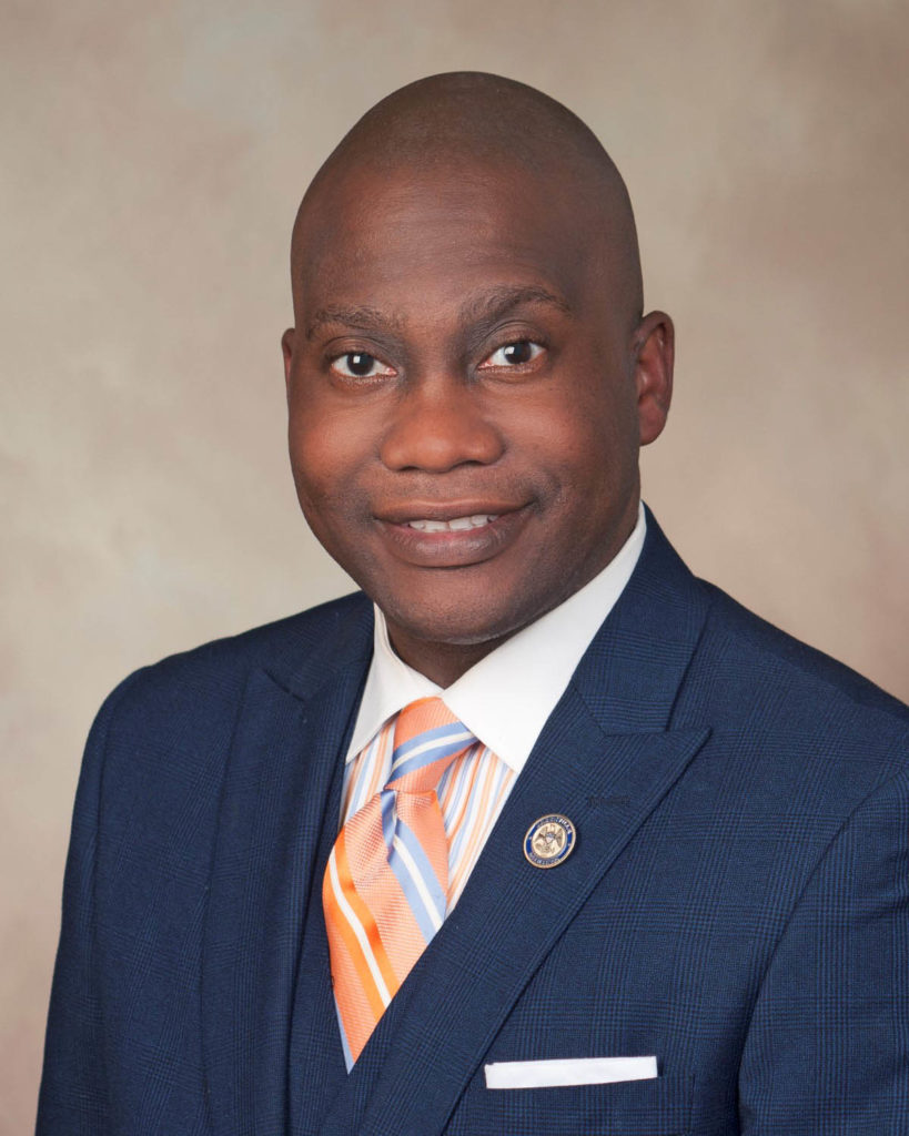 Headshot of Mayor Simmons, who wears a blue suit, white shirt, and striped tie.