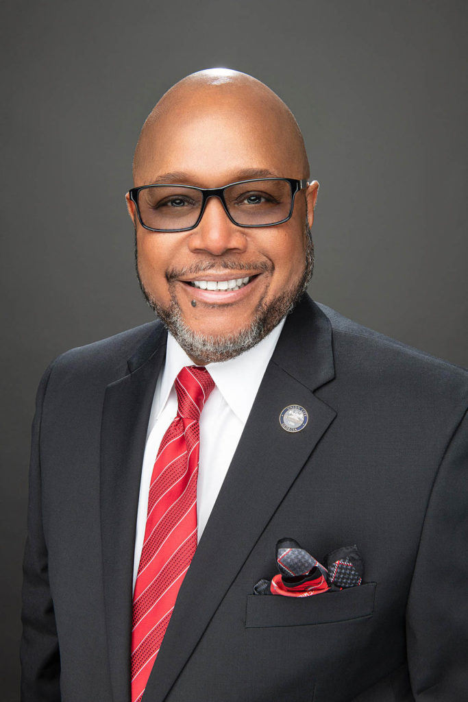 Headshot of Mayor Williams, who wears a black suit, white shirt, and red tie.