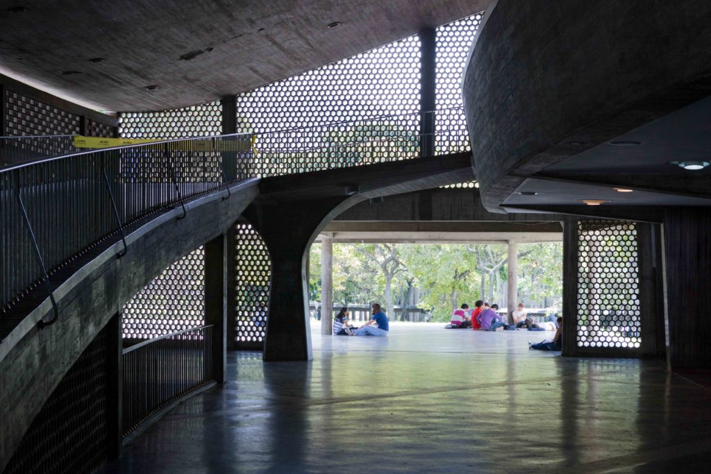 Image of interior looking to the exterior with people sitting at the distance