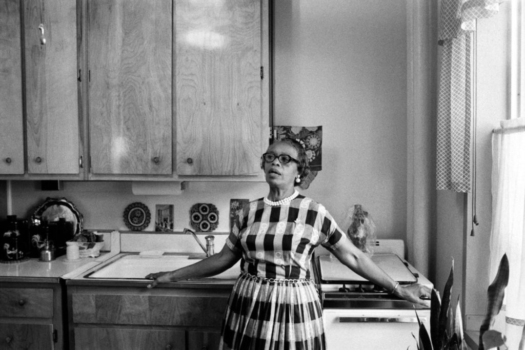 Black and white image of Chloe B. Hamilton standing in kitchen