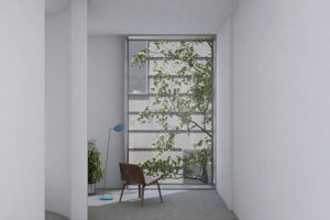 Interior of a housing project in Jamaica Plain, Boston. A chair, lamp, and potted plant sit in a room with white walls and a floor-to-ceiling sized window looking out at a tree and the side of the neighboring building.