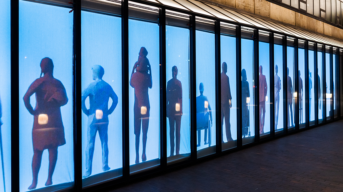 The Quincy Street facade of Gund Hall, showing a projection in the window of a line of individual people spaced evenly apart.