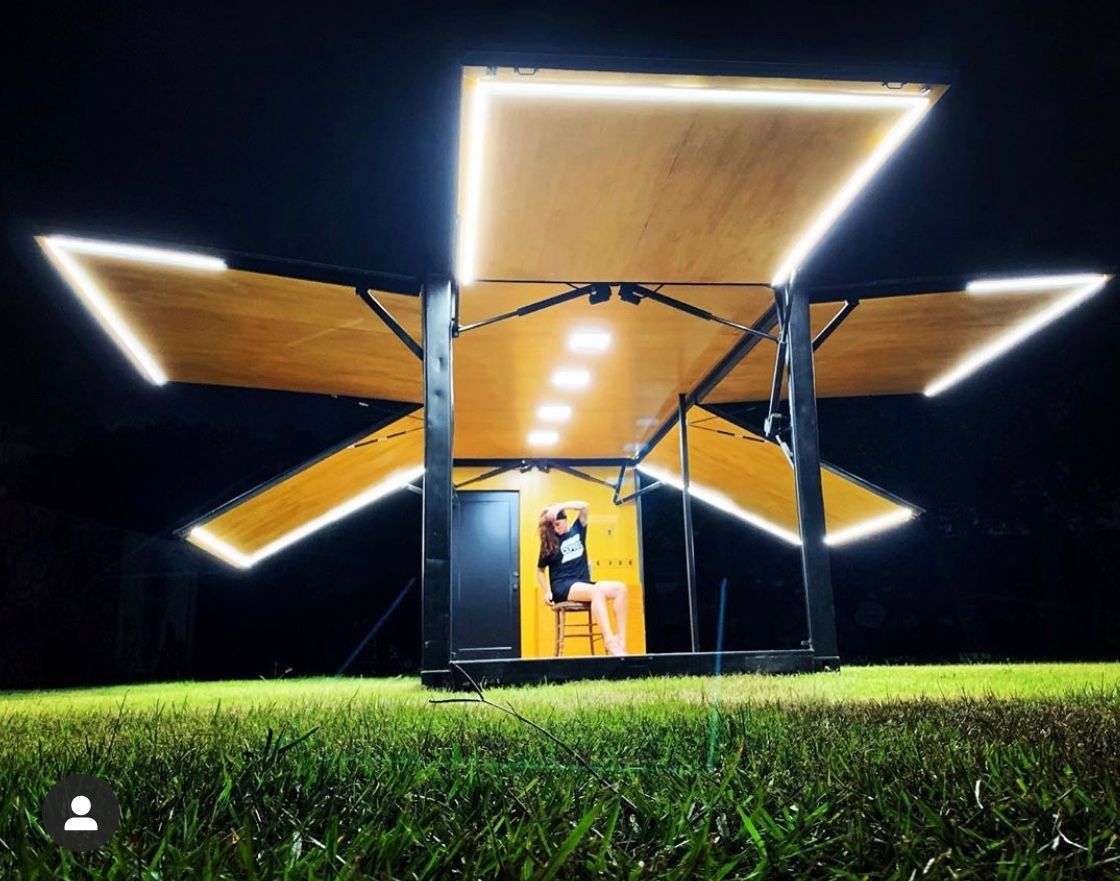 Outdoor exhibition with woman sitting inside pavilion.