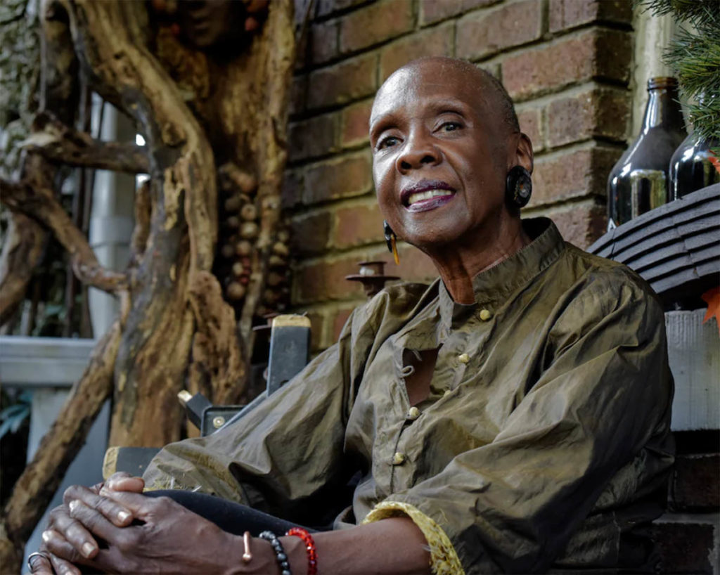 Anne Bouie wears an olive green shirt and sits, smiling.