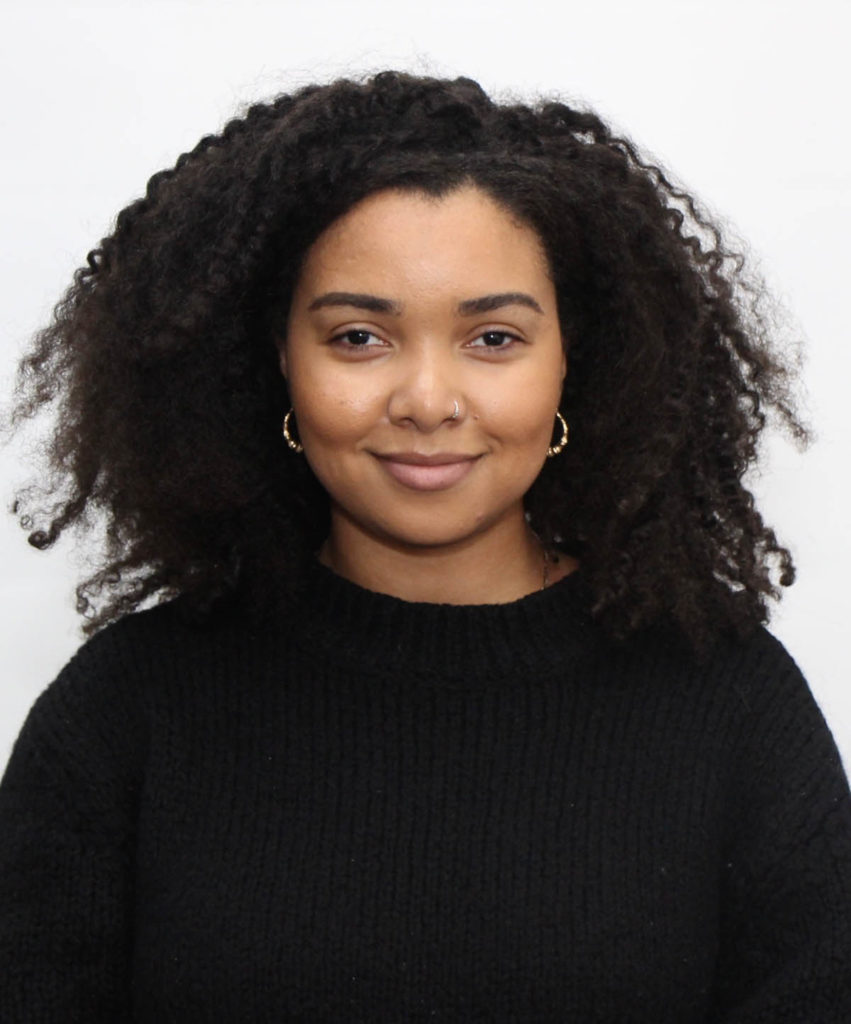 Headshot of Elleza Kelley, who wears a block sweater and small hoop earrings.