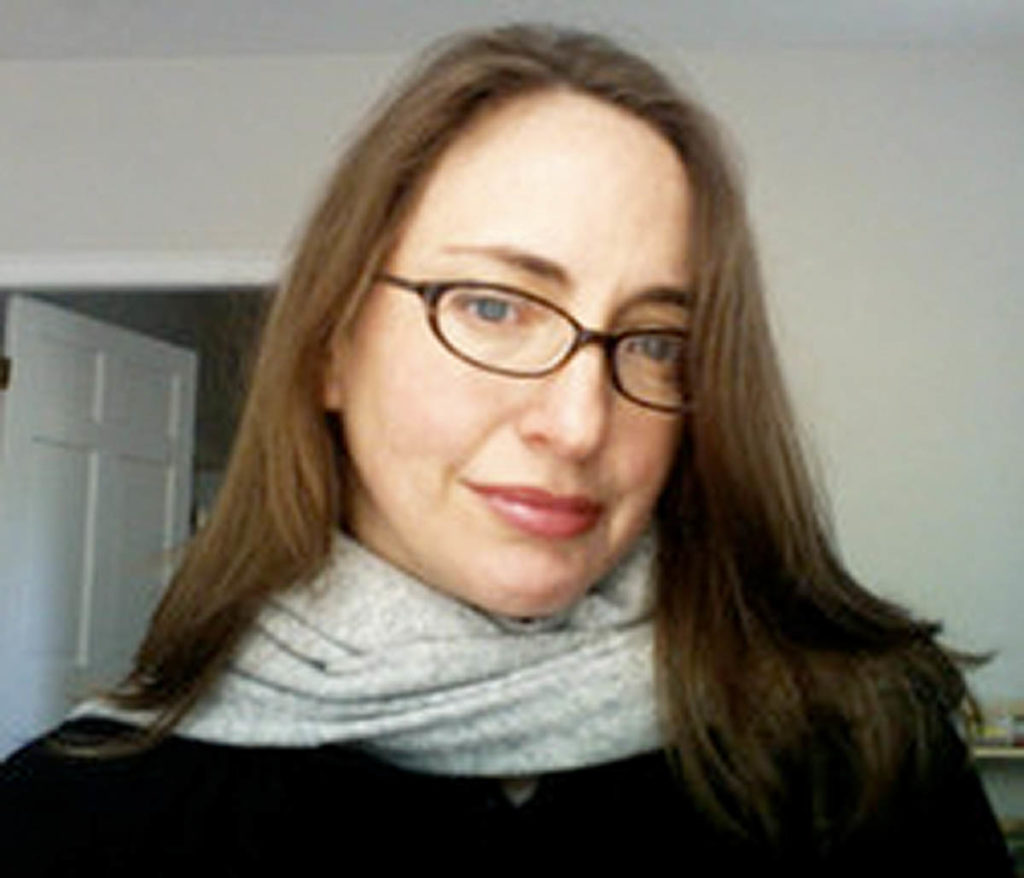 Headshot of Erika Naginski, who wears black glasses and a gray scarf. 