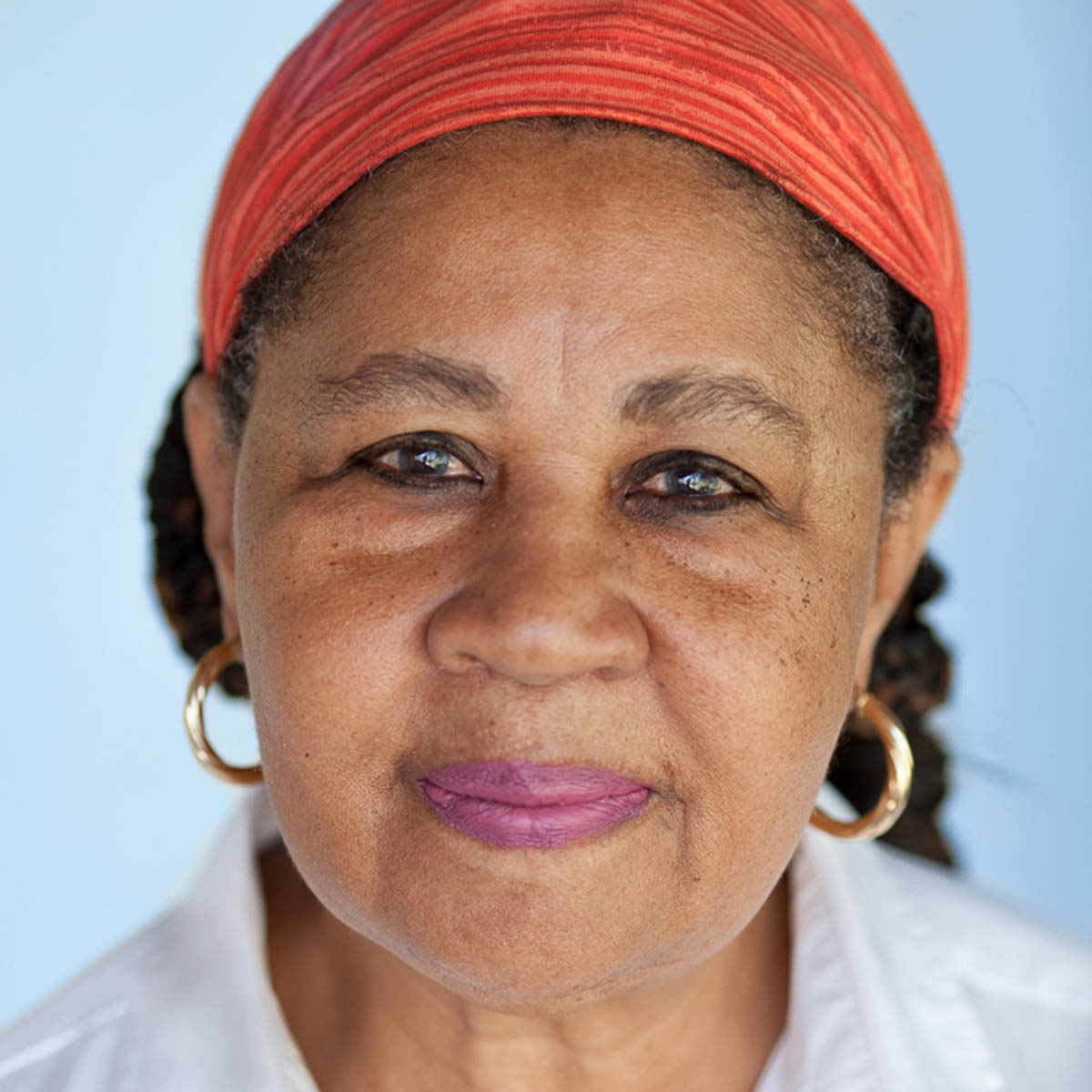 Headshot of Jamaica Kincaid, who wears hoop earrings and an orange head wrap.