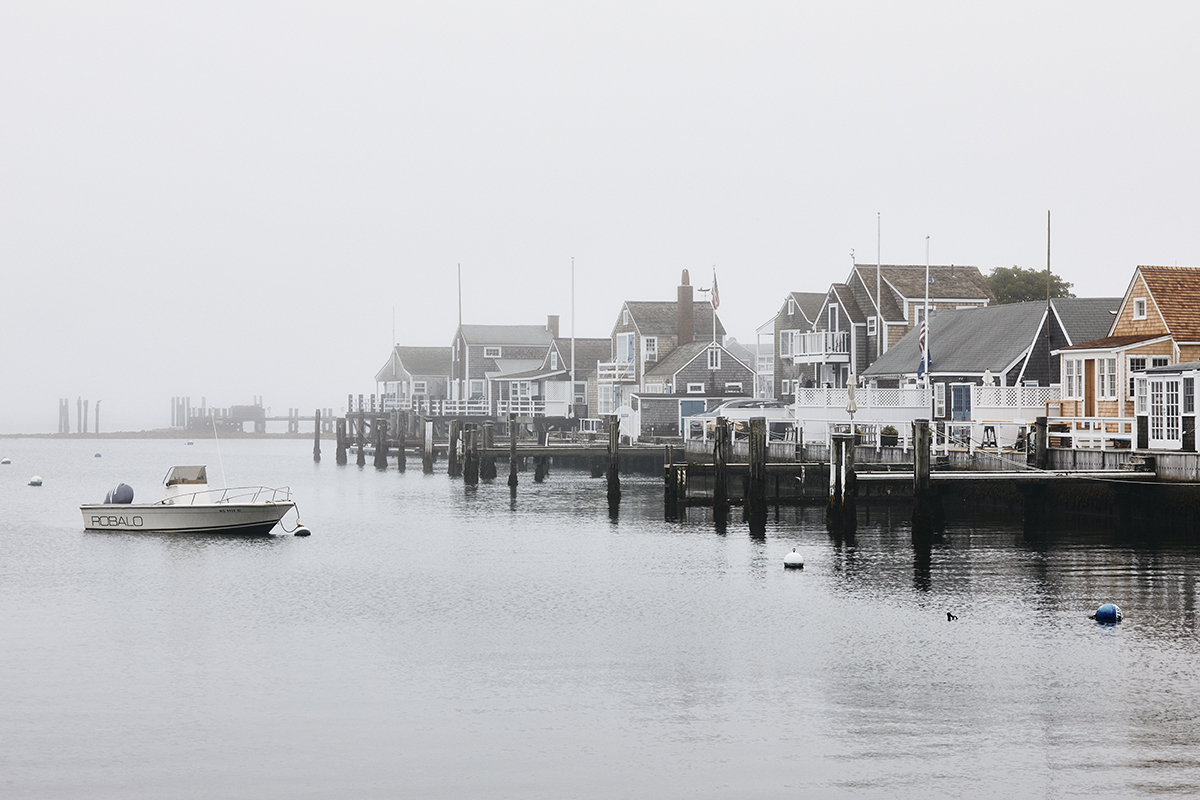 Houses and a boat on the water with morning fog