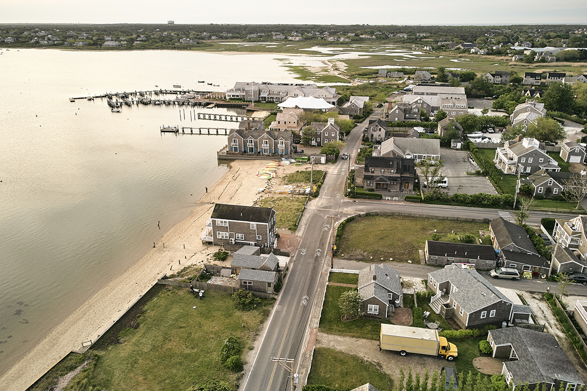 Road leading to houses in front of a beach