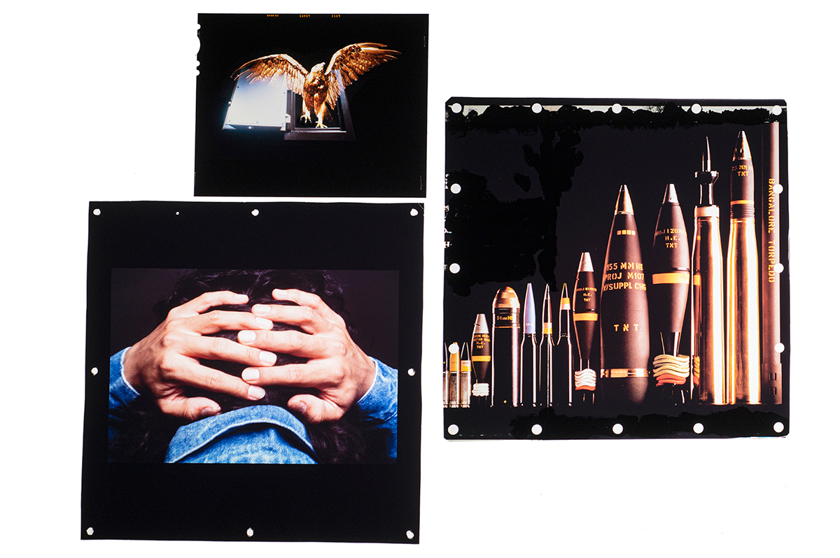 A detail of the light box showing an image of a bird, an image of a person with hands behind their head, and an image of missiles.