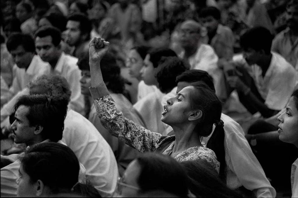 A central figure stands with their fist raised in a crowd of people.