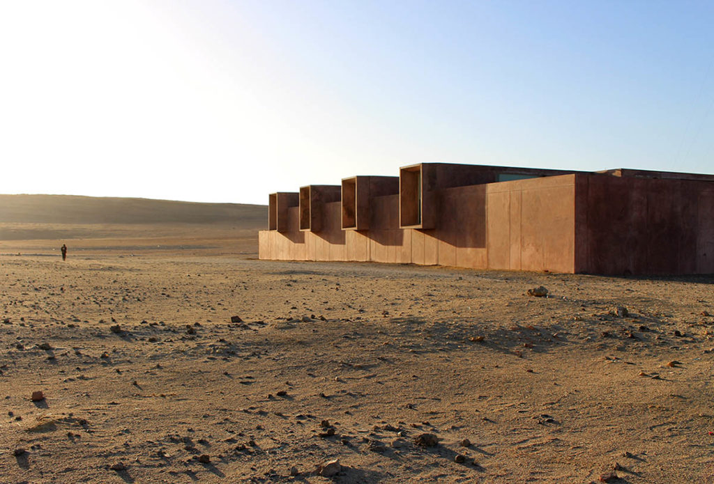 A bronze-colored building sits in a desert landscape.