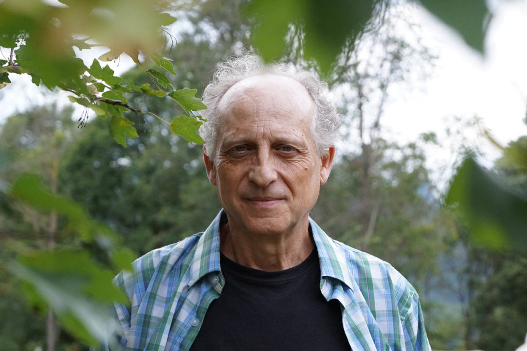 Joan Nogué stands outdoors, surrounded by leaves.