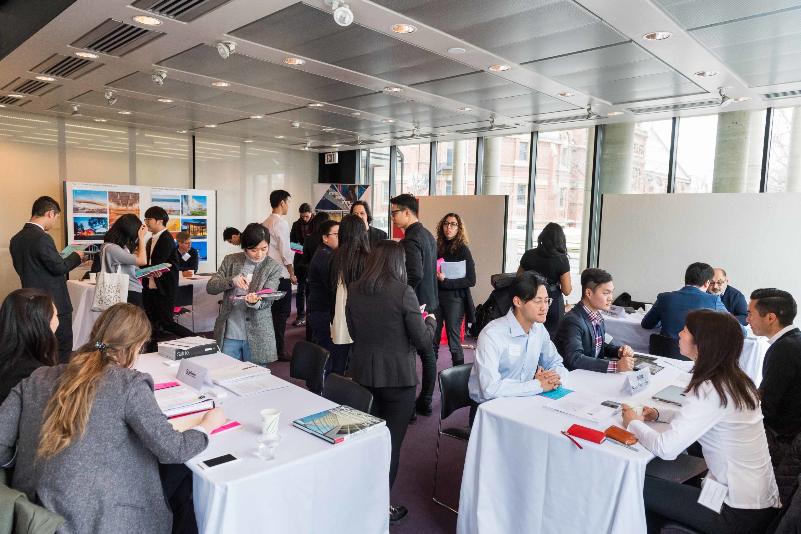 Image of the GSD Career Fair, with booths of employers set up, and students sitting down to meet with them