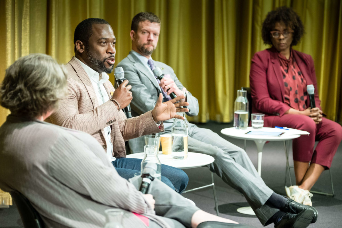 Levar M. Stoney speaks into a microphone surrounded by three other panelists.