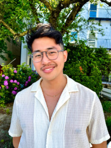 Headshot of Shane Ah-Siong in front of a flowering tree.