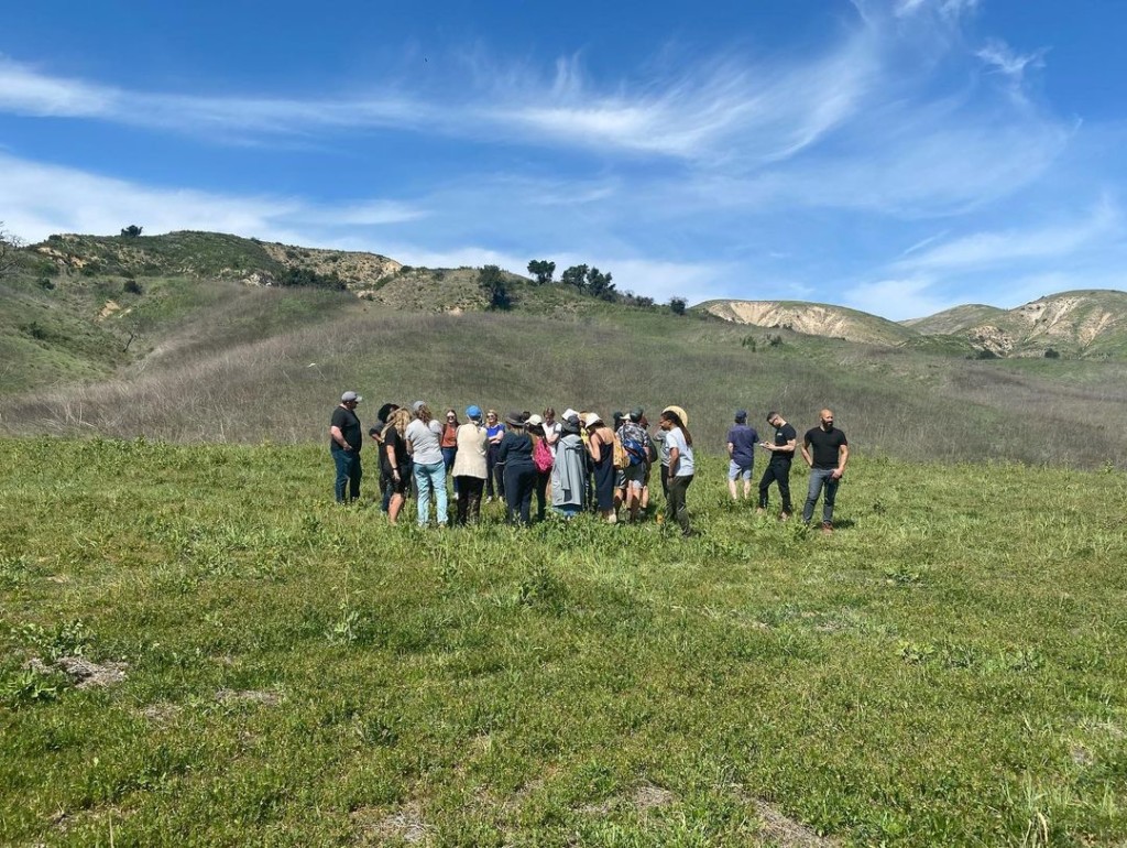 A group is gathering in the middle of a green space.