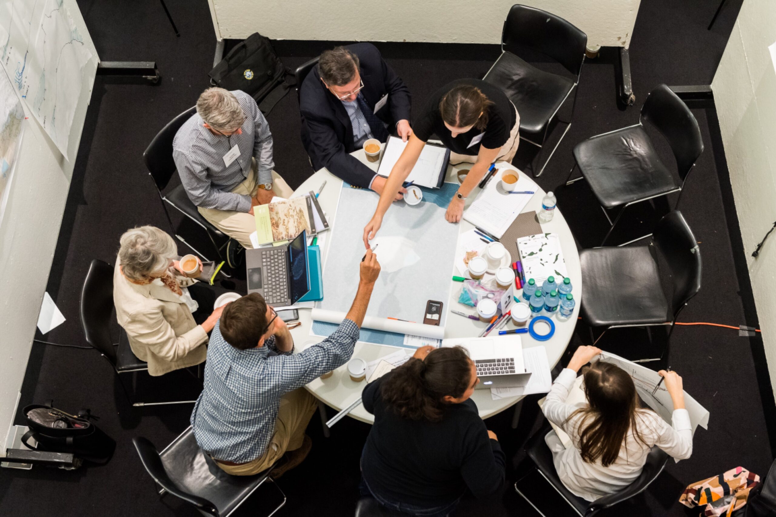 Seven people sit around a table brainstorming