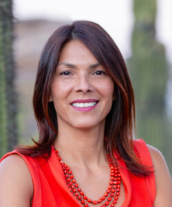 Headshot of Wanda Dalla Costa, who wears a red-orange shirt and necklace.