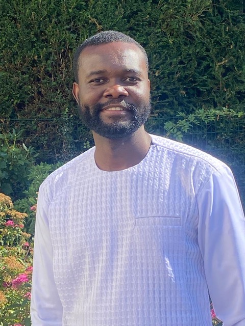 Portrait of Emmanuel Kofi Gavu smiling in front of greenery.