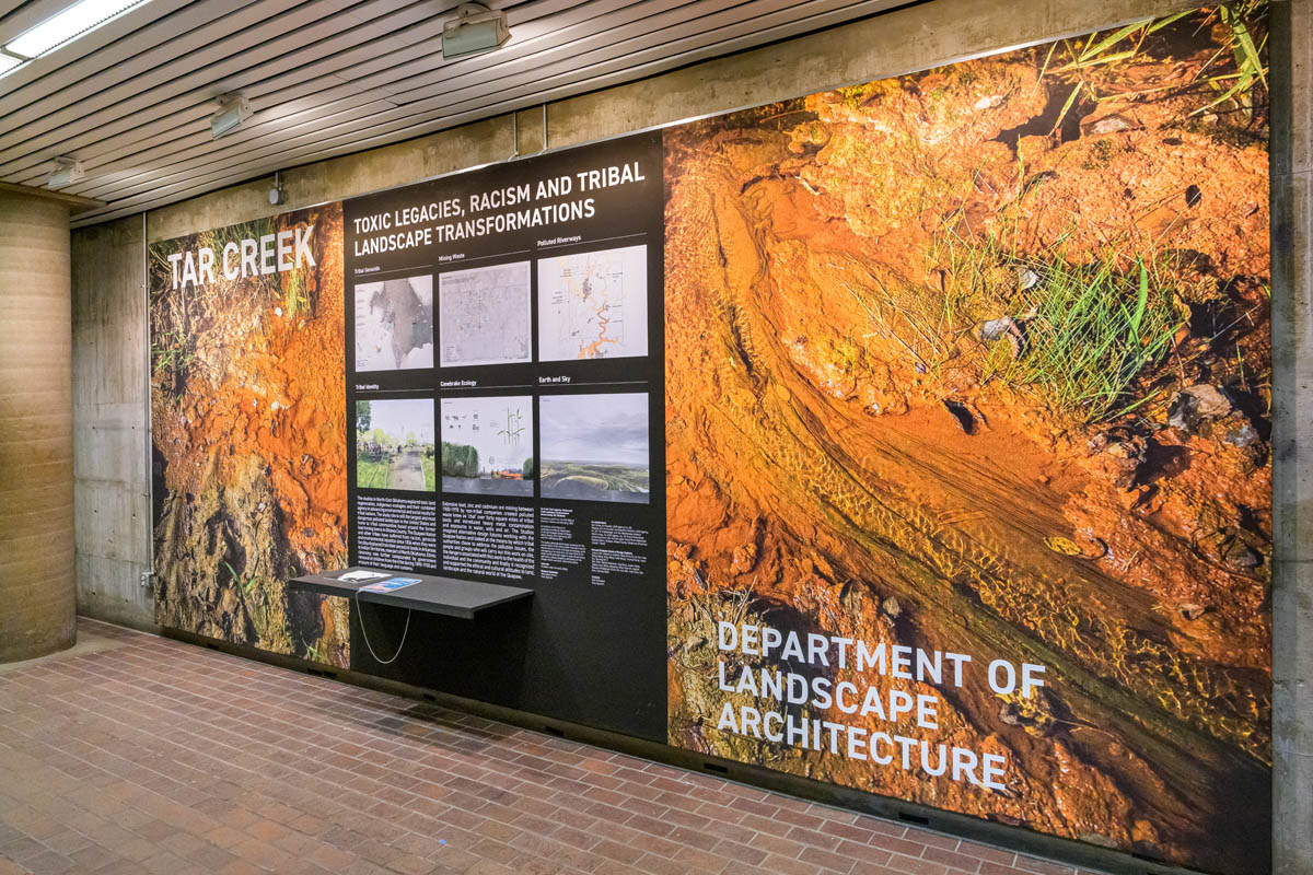 Exhibit wall with a large orange image of a saturated and polluted river bed.