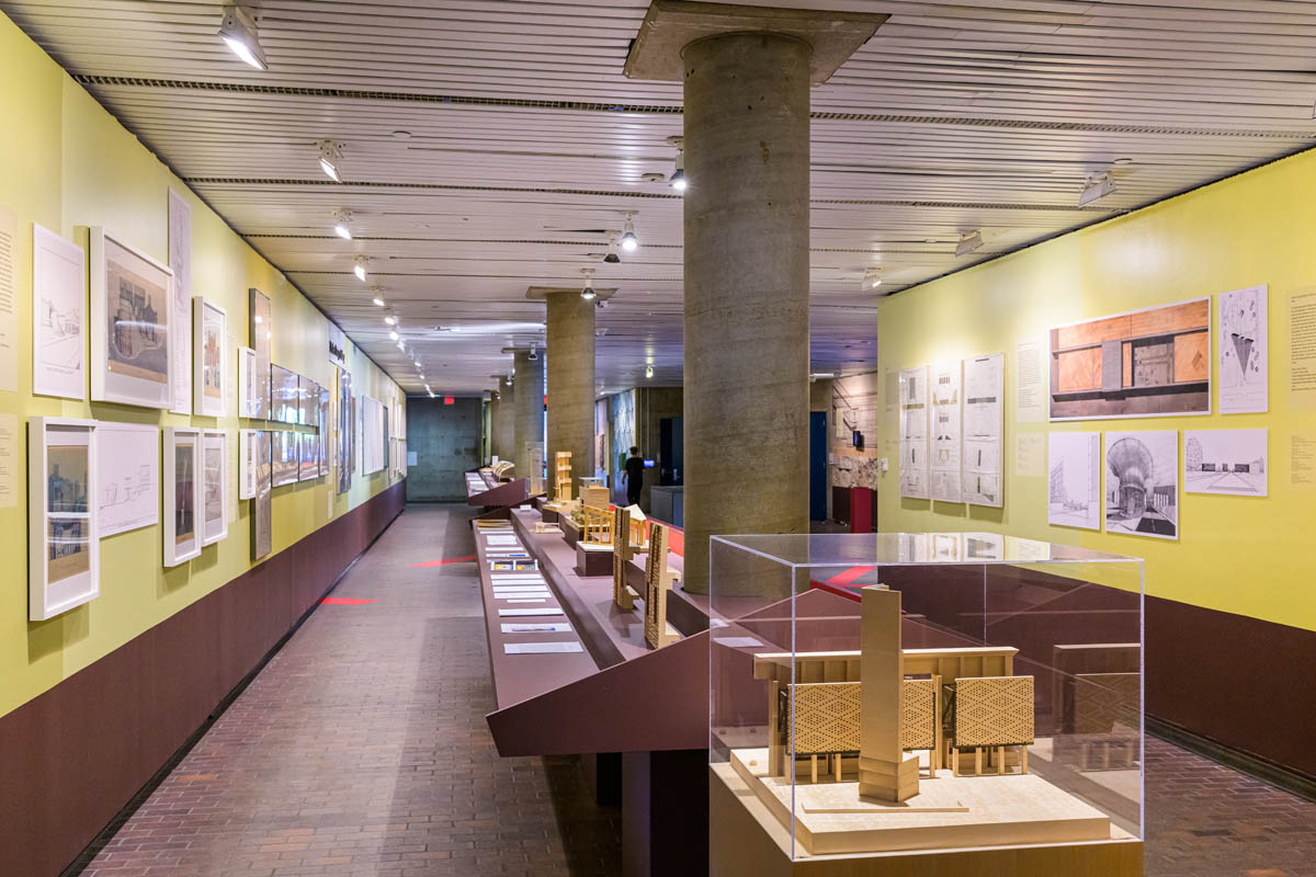 looking down the gallerry cooridor. The walls have framed drawings and full-scale facsimiles. Down the center of the cooridor are long shelves of models, books, text facsimiles and vitrines containing archival artifacts.