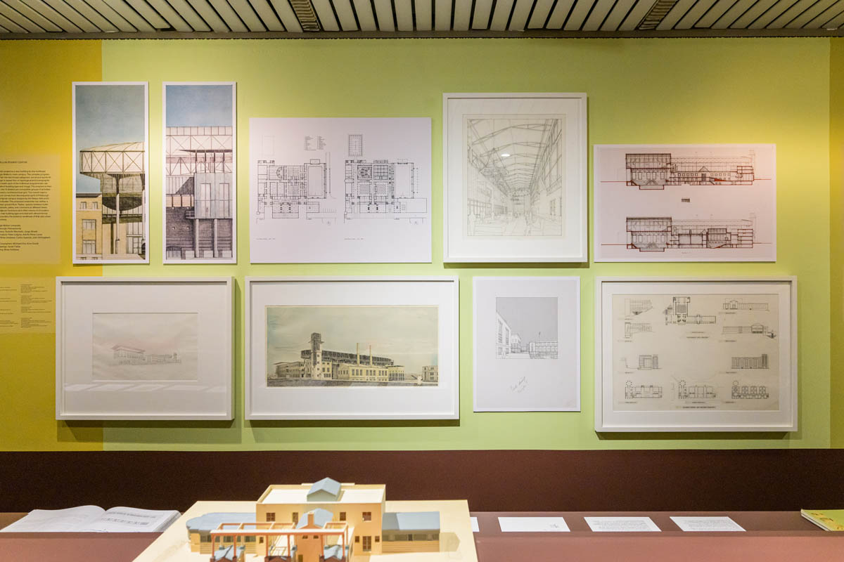 A wall of framed drawings and full-scale facsimiles. In the forground is a model.
